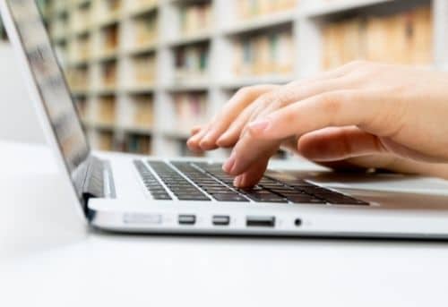 Hands typing on a laptop keyboard of person doing the best daily transcription jobs