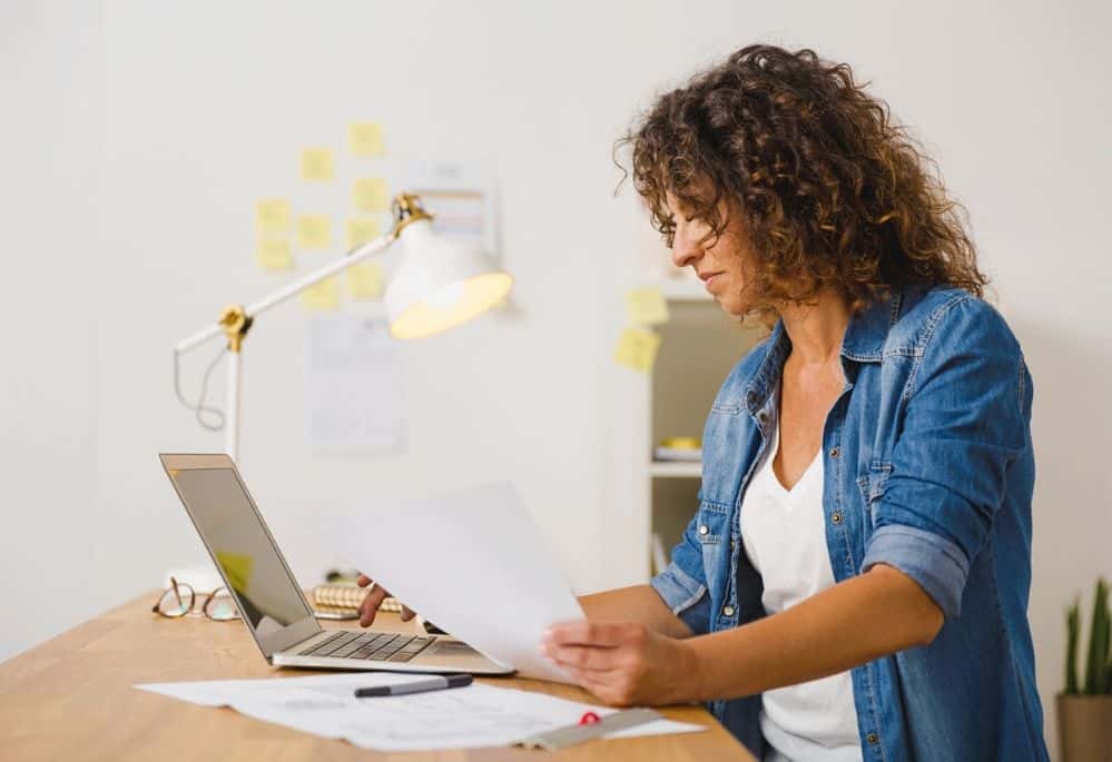 woman proofreading document using laptop