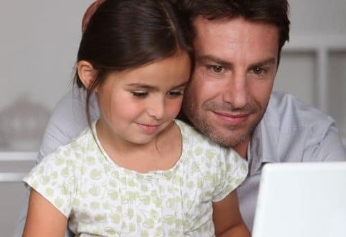 Dad working at home on laptop with daughter