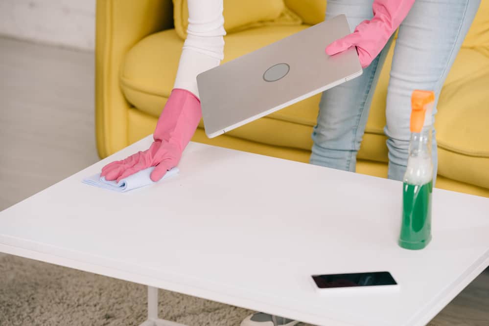 Woman cleaning home work station with laptop and smartphone during natural health disaster.