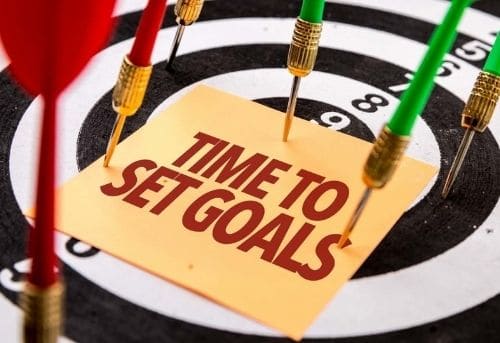 Image of dart board and darts with a  pinned card with text saying time to set goals as the third resolution