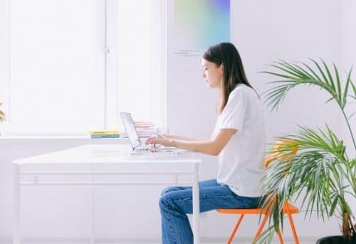 image of woman sitting at home desk working from home by making money on Fiverr